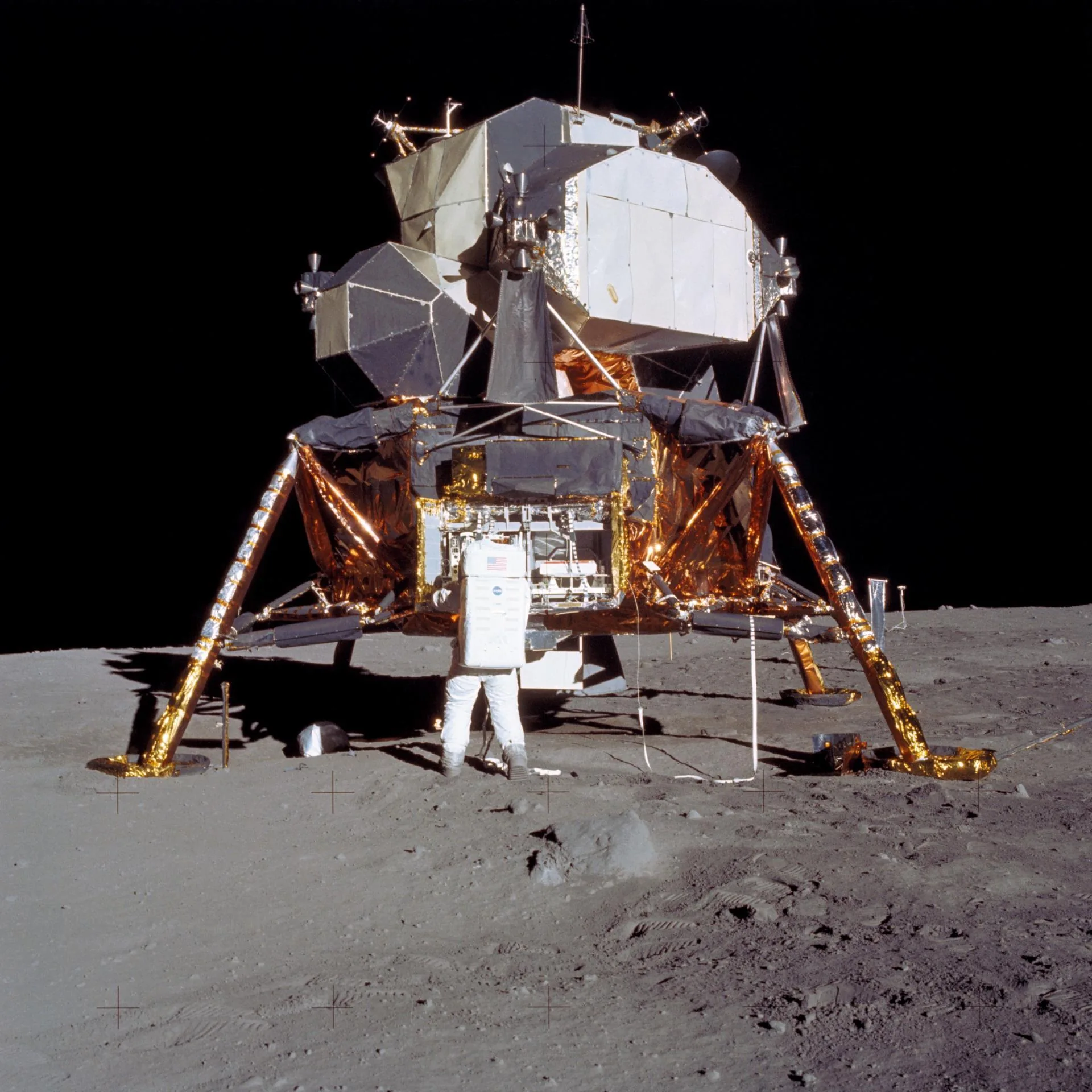 Módulo lunar Eagle del Apolo 11 sobre la Luna, con Buzz Aldrin retirando instrumentos científicos y las patas de aterrizaje visibles.
