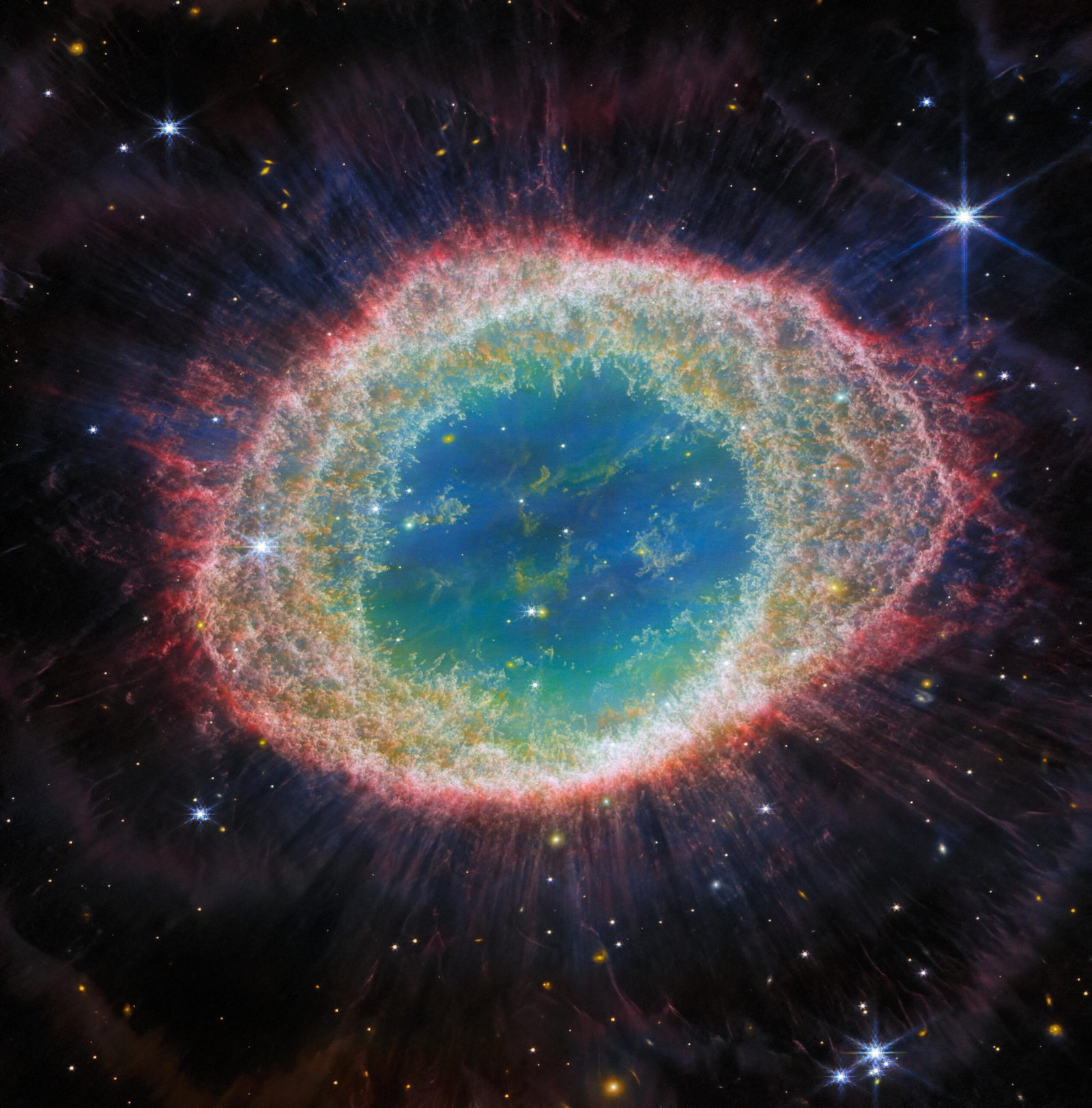 Nebulosa del Anillo M57 observada por James Webb, con capas de gas anaranjado y rosado que rodean una región central azul verdosa.